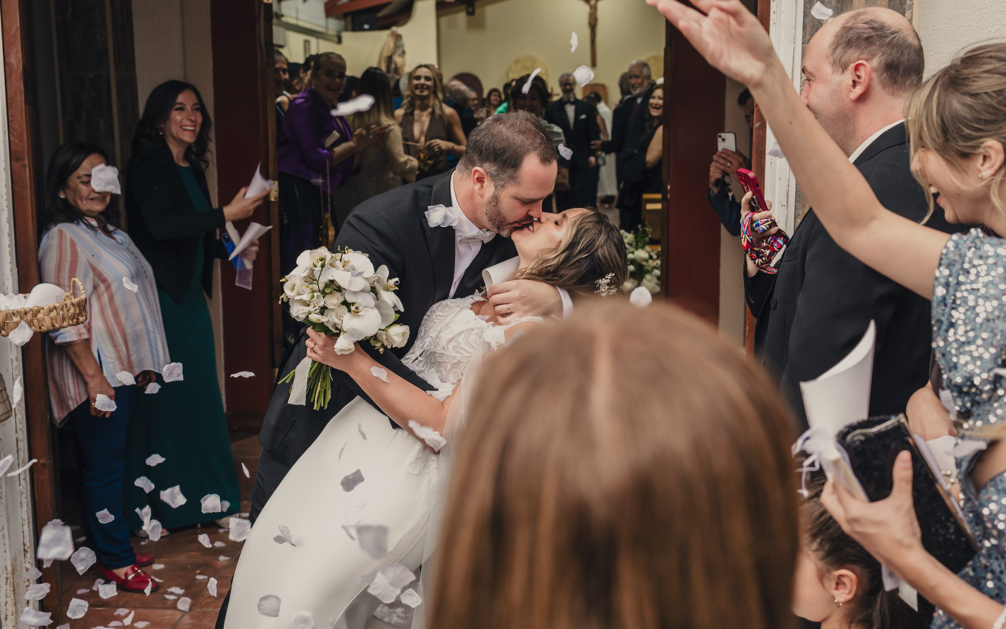 Los novios se besan a la salida de la iglesia entre pétalos