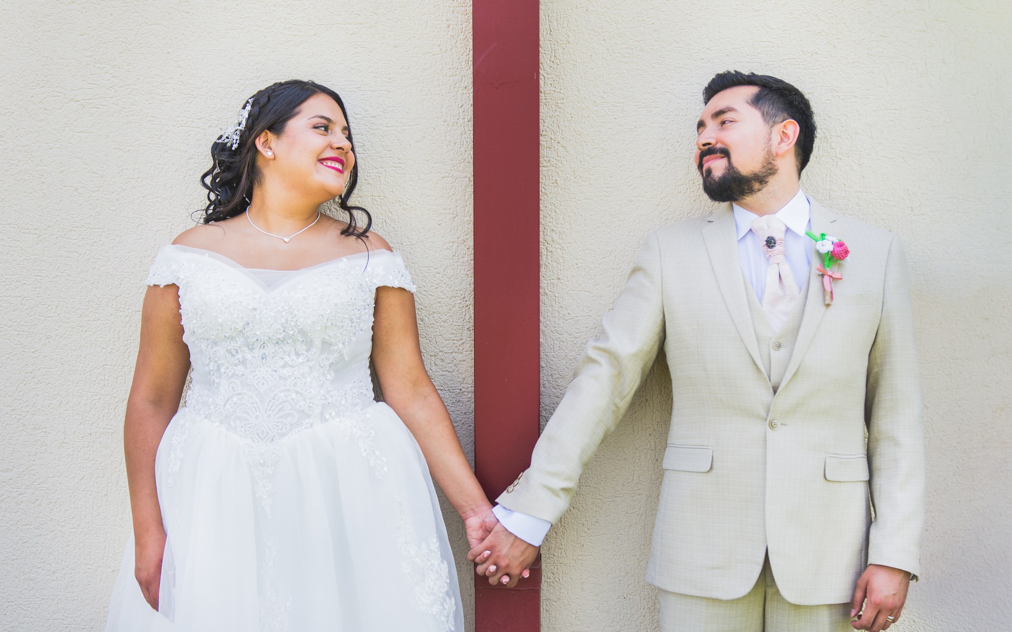 Novios tomados de la mano, apoyados en un muro